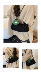 Détail du sac nuage noir à texture bulle avec un charm fleur verte sur la bandoulière