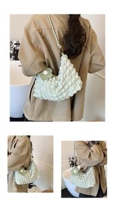 Détail du sac à bandoulière plissé vert clair avec pendentif fleur et lanière