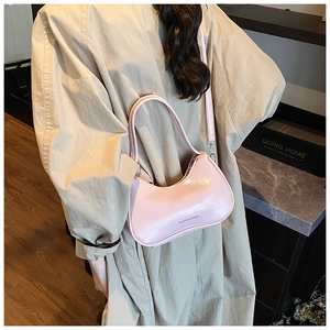 Detail of pink crescent shoulder bag in glossy patent leather with adjustable straps