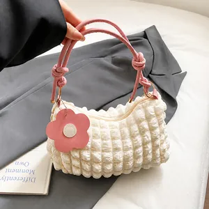 Dettaglio della borsa a pieghe bianca con manico annodato rosa e ciondolo a fiori