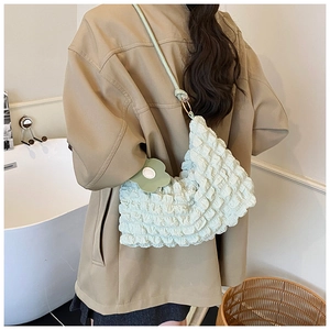 Détail du sac à main vert clair plissé avec accessoire de charme floral décoratif