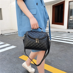 Chic black quilted PU leather handbag with gold zippers and detachable strap worn by model