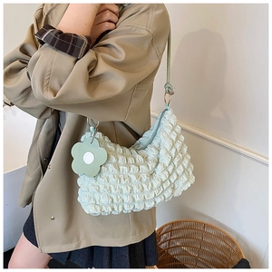 Détail du sac plissé vert clair avec breloque fleurie et bandoulière à nœuds élégante