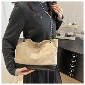 Détail du sac cabas matelassé en daim beige et cuir noir avec bandoulière chaîne dorée