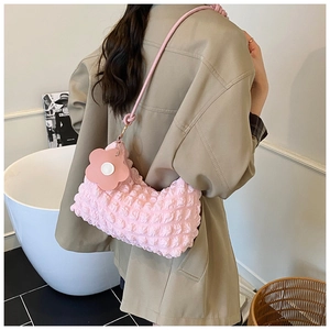 Sac à bandoulière rose texturé à bulles avec charm fleur porté avec un trench-coat