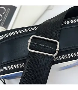 Détail de la bandoulière réglable en nylon avec boucle argentée sur un sac noir en cuir