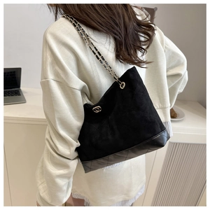 Detail of black quilted tote bag with gold chain strap and diamond stitching on shoulder
