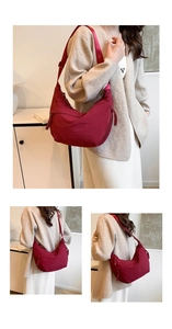 Close-up of wine red nylon crescent bag featuring wide shoulder strap and woven zipper pull