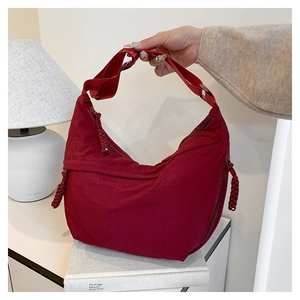 Detail of dark red nylon crescent bag with adjustable wide strap and woven zipper puller