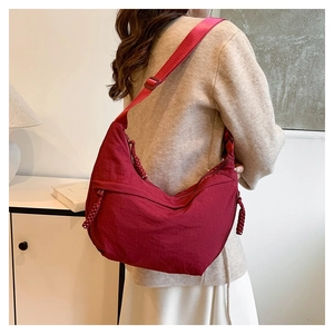 Detail of burgundy nylon crescent bag with adjustable strap and textured fabric finish