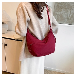 Detailed back view of a burgundy nylon crescent crossbody bag with woven zipper pull details