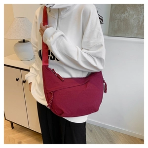 Close-up of burgundy nylon crescent bag with woven knot zipper and adjustable strap
