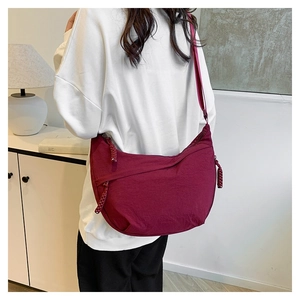Close-up of wine red nylon crescent bag featuring ruched texture and woven zipper detail