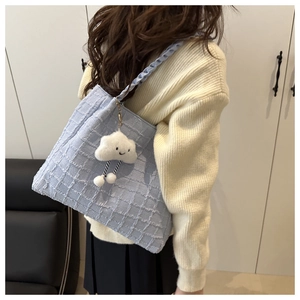 Detail of light blue checkered tote bag with woven strap and a plush cloud charm
