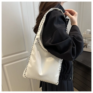 Detail of white soft leather tote bag featuring elegant silver stud trim on the edges