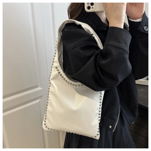 Close-up of white leather underarm bag with silver rivet studs for stylish daily wear