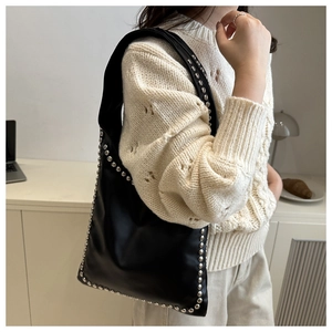 Close-up of black leather shoulder bag with vintage silver rivets and side stud details