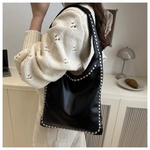 Detail of silver round metal rivets on black leather shoulder bag with a stylish design
