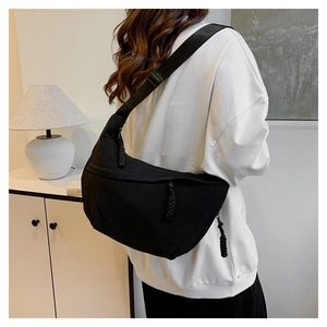 Rear view of a model wearing a black nylon crescent shoulder bag with woven zip puller