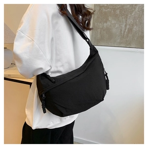 Detail of black nylon crescent crossbody bag featuring woven knot zipper pullers
