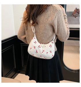 Detail of white corduroy underarm bag with red cherry pattern on model back view