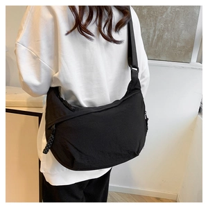 Detail of adjustable strap and woven zipper pull on black nylon crossbody bag