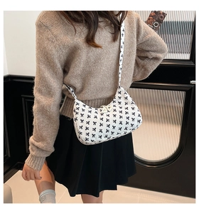 Détail de sac sous l'épaule blanc à imprimé nœuds noirs porté par un mannequin
