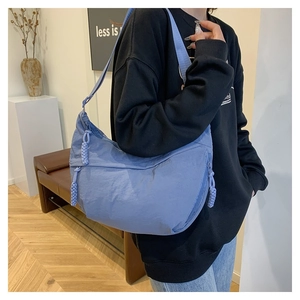 Detail of blue nylon crescent bag featuring a woven rope zipper and side pocket