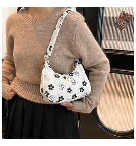 Close-up of white corduroy hobo bag featuring black and white floral pattern and wide strap