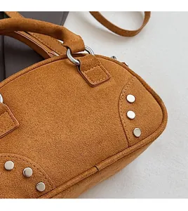 Detail of brown suede handbag featuring silver stud accents and metallic hardware texture