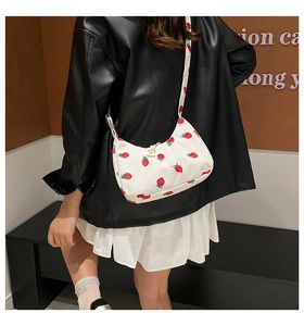 Close-up of strawberry print corduroy shoulder bag carried by a model in casual outfit