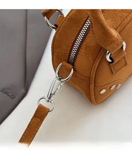 Close-up of silver metal zippers and D-ring hardware on a brown suede bowling handbag