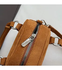 Detailed macro view of the silver metal zipper and brown suede material on the handbag