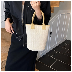 Detail of woven bucket bag featuring white herringbone pattern and soft fabric handles