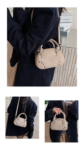Detail of beige suede Boston bag with metal rivets and adjustable shoulder strap