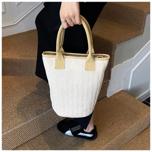 Detail view of woven bucket bag with fishtone texture and contrasting webbed handle