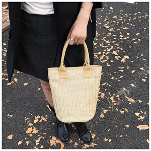 Detailed herringbone weave texture on a beige woven bucket bag held outdoors