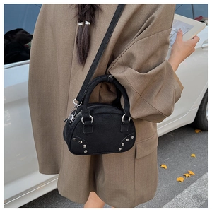 Outdoor street style shot of black suede bowling bag with silver studs and wide strap