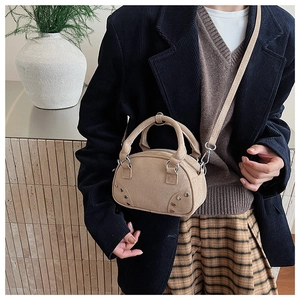 Beige suede bowling bag with silver studs worn by a model in vintage style