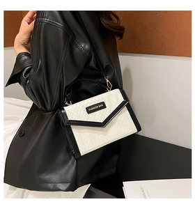 Detail of black and white woven texture handbag with golden metal hardware and branding