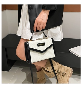 Close-up of woven handbag with V-shaped flap and black and white contrast design details