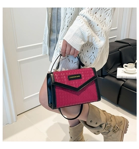 Detail of woven texture handbag with magenta and black contrast colors and logo