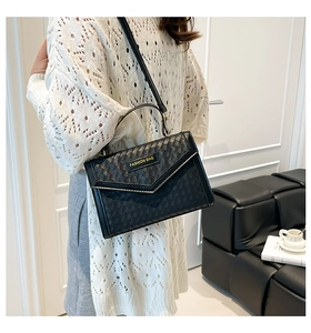Detail of black woven texture handbag with gold Fashion Bag logo and V-flap closure