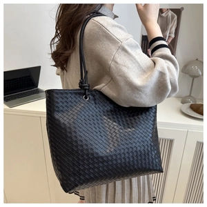 Detail of black woven leather tote bag with long shoulder straps in a modern office