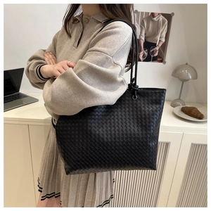 Detailed view of the woven leather texture and silver metal rings on a black tote bag