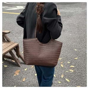 Detail of a large woven leather tote bag in dark brown with a cross-weave pattern