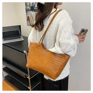 Detailed view of brown woven tote bag with leather texture and thin shoulder straps