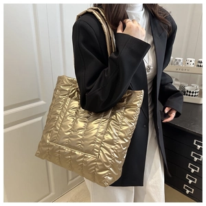 Detailed view of large golden quilted tote bag with metallic finish and down-padded texture