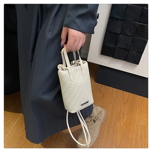Détail d'un mini sac tressé avec doubles poignées et texture beige élégante