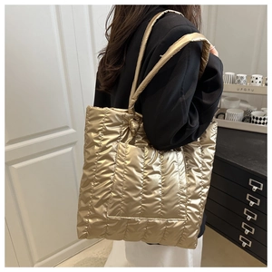Detailed view of champagne gold quilted tote bag with metallic gloss and padded texture